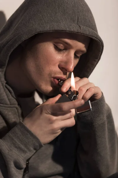 Gros plan de l'homme dans la capuche éclaircissant pipe à fumer — Photo de stock