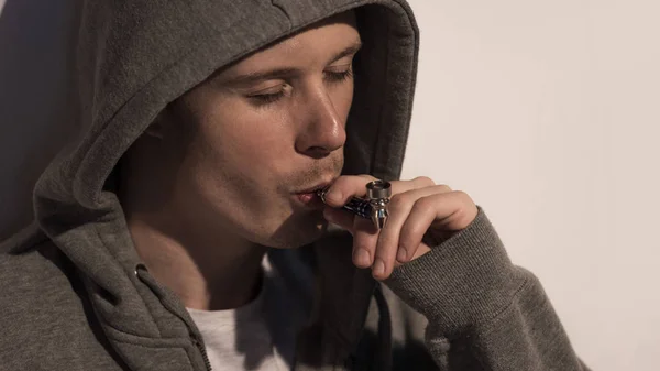 Junkie-Mann in Kapuze raucht Pfeife mit geschlossenen Augen — Stockfoto