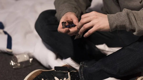 Selective focus of man holding smoking pipe and pack of marijuana — Stock Photo