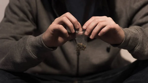 Selective focus of junkie man opening pack with marijuana — Stock Photo