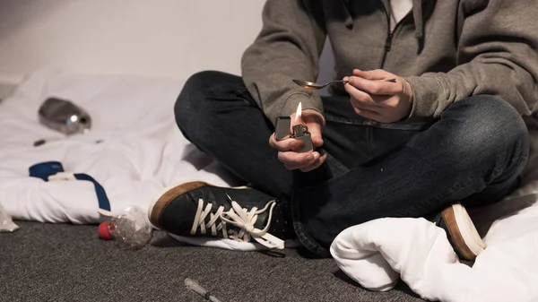 Visão parcial do viciado homem fervendo heroína na colher no isqueiro — Fotografia de Stock