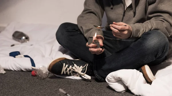 Vue partielle de l'homme toxicomane bouillir de l'héroïne dans la cuillère sur briquet — Photo de stock