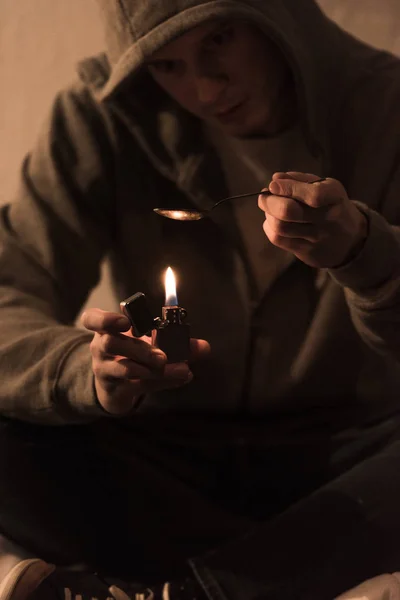 Selective focus of addict man boiling heroin in spoon on lighter — Stock Photo