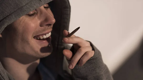 Addict man under drug influence holding rolled marijuana cigarette — Stock Photo