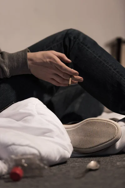 Selective focus of junkie man holding rolled marijuana cigarette — Stock Photo