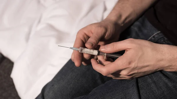 Selective focus of narcomaniac man holding syringe with dose of heroin — Stock Photo