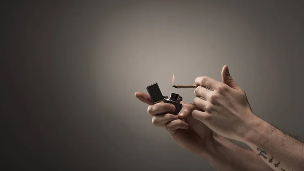 Vue partielle de la cigarette de marijuana roulée éclaircissante masculine sur fond gris — Photo de stock