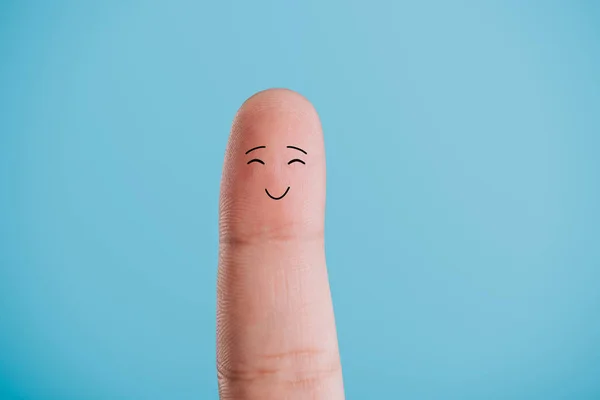 Vista cortada de um dedo com rosto sorridente isolado em azul — Fotografia de Stock