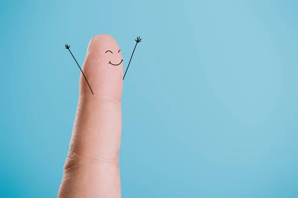 Обрезанный вид одного пальца со счастливым лицом, изолированным на голубом — стоковое фото