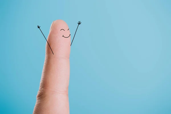 Vista recortada de un dedo con la cara feliz aislado en azul - foto de stock