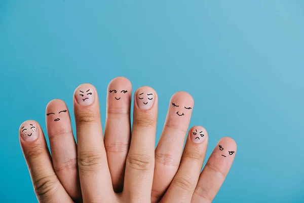 Vista recortada de los dedos humanos con diferentes emociones aisladas en azul - foto de stock