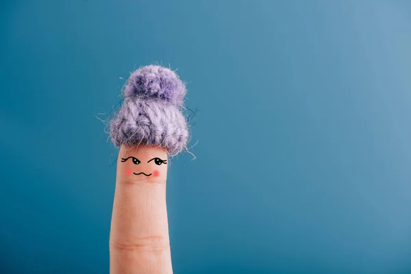 Vista ritagliata di un dito in cappello lavorato a maglia isolato su blu — Foto stock