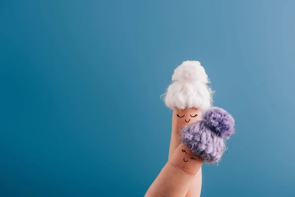 Vue recadrée des doigts comme des femmes rêveuses dans des chapeaux tricotés isolés sur bleu — Photo de stock