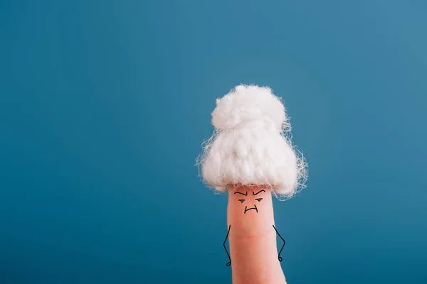 Vista recortada del dedo como anciana en sombrero de punto con mal humor aislado en azul - foto de stock