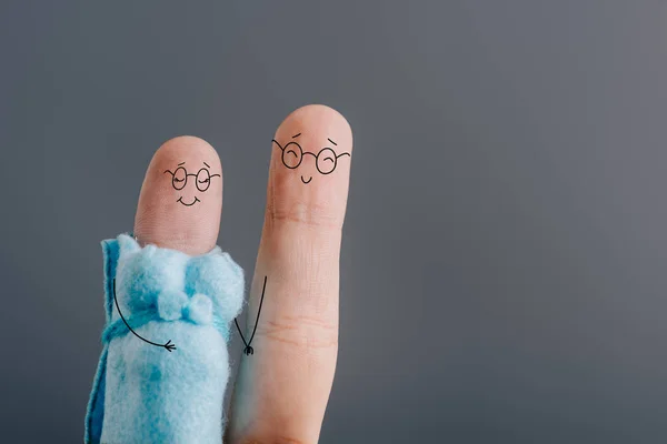 Cropped view of fingers as smiling pregnant couple in glasses holding hands isolated on grey — Stock Photo