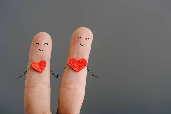 Vista recortada de feliz par de dedos con corazones tomados de las manos aislados en gris, concepto de día de San Valentín - foto de stock