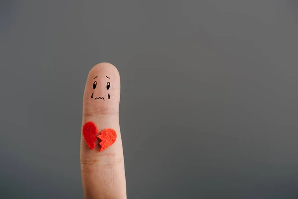 Обрізаний вид одного засмученого пальця з розбитим серцем ізольовано на сірому — стокове фото