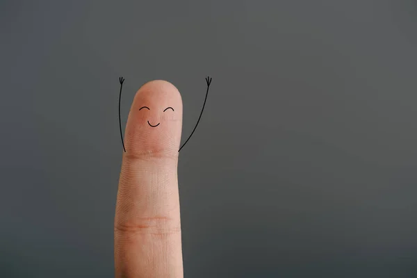 Vista recortada de un dedo con la cara sonriente aislada en gris - foto de stock