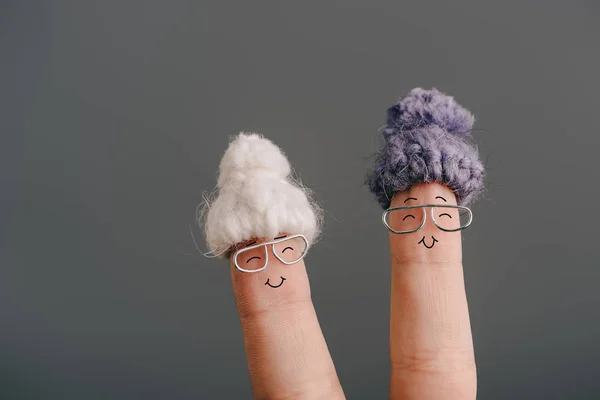 Vue recadrée des doigts comme des femmes âgées souriantes dans des chapeaux tricotés isolés sur bleu — Photo de stock