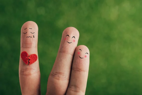 Vista recortada de los dedos como pareja feliz y persona con el corazón roto en verde - foto de stock