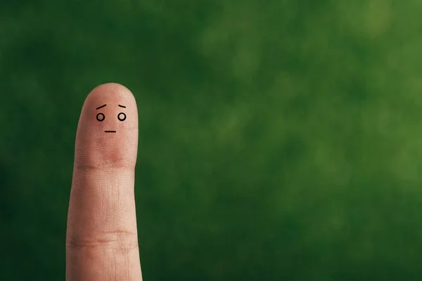 Обрізаний вид одного пальця зі збентеженим обличчям на зеленому — стокове фото