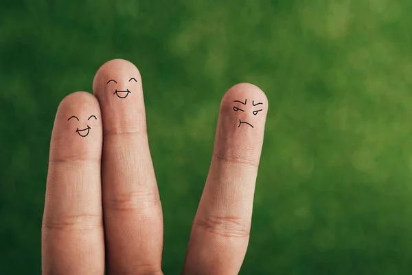 Cropped view of happy fingers and one dissatisfied on green — Stock Photo