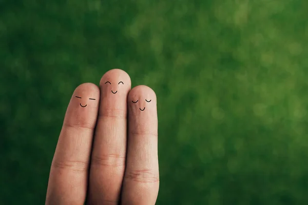 Vista recortada de los dedos humanos sonrientes en verde - foto de stock