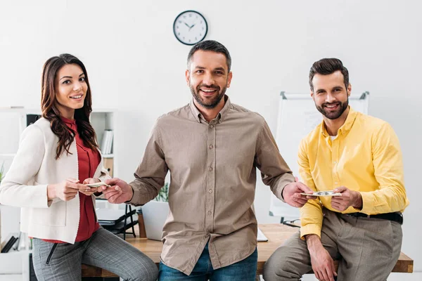 Advisor standing and taking money from man and woman in office — Stock Photo