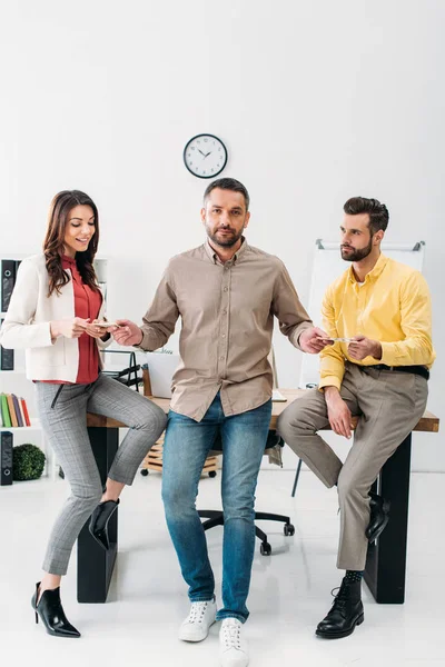 Advisor standing and giving money to man and woman near table in office — Stock Photo