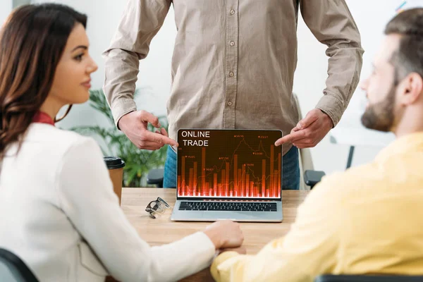 Foyer sélectif du conseiller pointant avec les doigts à l'ordinateur portable avec le site de commerce en ligne à l'écran à l'homme et à la femme au bureau — Photo de stock