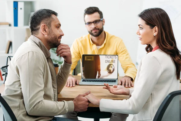 Foyer sélectif de l'homme et de la femme tenant la main près du conseiller et de l'ordinateur portable avec des billets site en ligne dans le bureau — Photo de stock