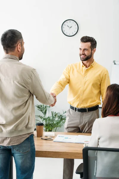 Conseiller et investisseur serrant la main d'une femme de table assise au bureau — Photo de stock