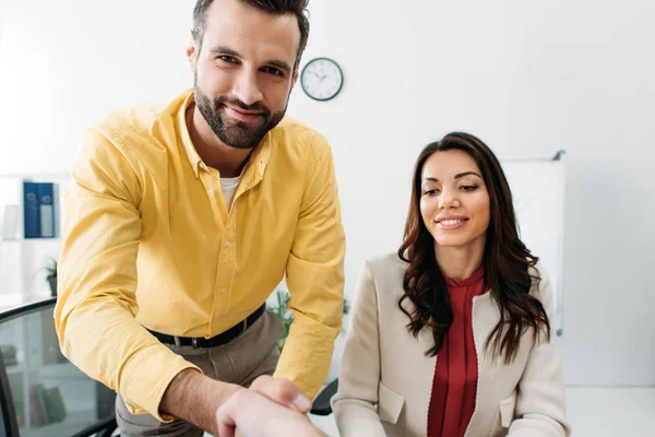 Selektiver Fokus des Investors beim Händeschütteln mit Beraterin und Frau am Tisch im Büro — Stockfoto