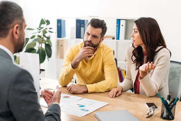 Investors sitting at table and thinking near advisor in office — Stock Photo