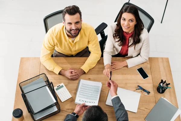 Vista de ángulo alto del asesor que da contrato a los inversores en la mesa en el cargo - foto de stock