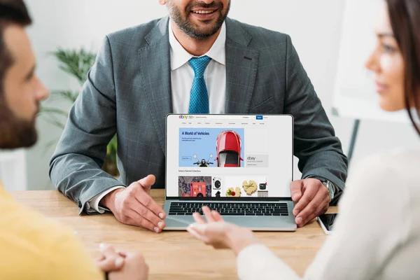 Vista ritagliata del consulente seduto a tavola e laptop con sito web ebay sullo schermo con gli investitori in ufficio — Foto stock