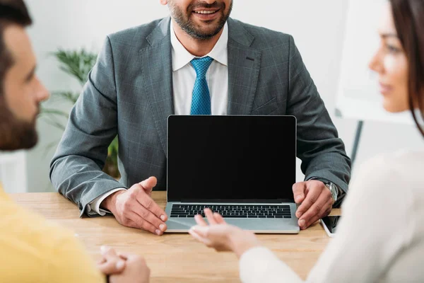 Vista cortada do conselheiro sentado à mesa e laptop com tela em branco com investidores no escritório — Fotografia de Stock