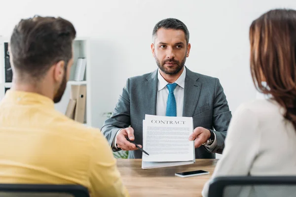 Selektiver Fokus des Beraters, der am Tisch sitzt und mit dem Stift auf die Investoren im Büro zeigt — Stockfoto