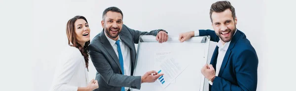 Colleagues standing near stand with document and smiling isolated on white — Stock Photo