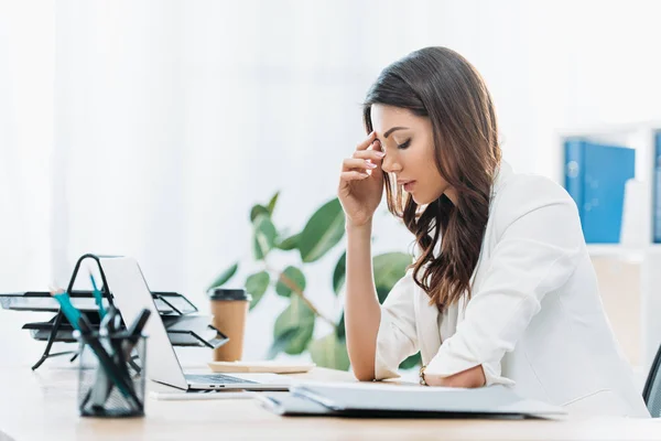 Donna d'affari sconvolta seduta a tavola e in cerca di laptop in ufficio — Foto stock