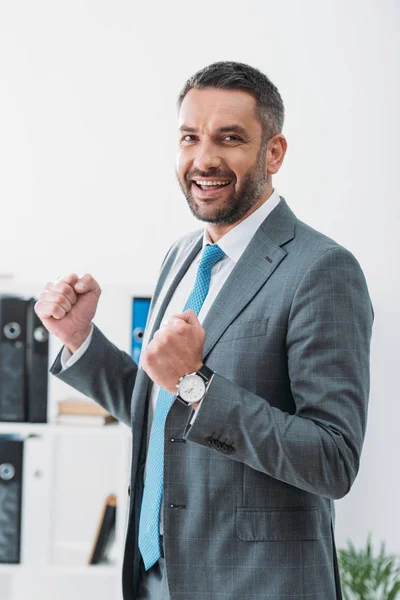 Homem de negócios bonito em terno cinza mostrando sim gesto no escritório — Fotografia de Stock