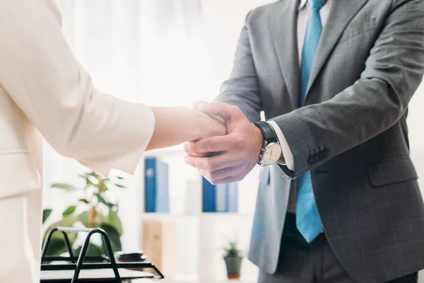 Visão parcial de homem e mulher em ternos apertando as mãos — Stock Photo