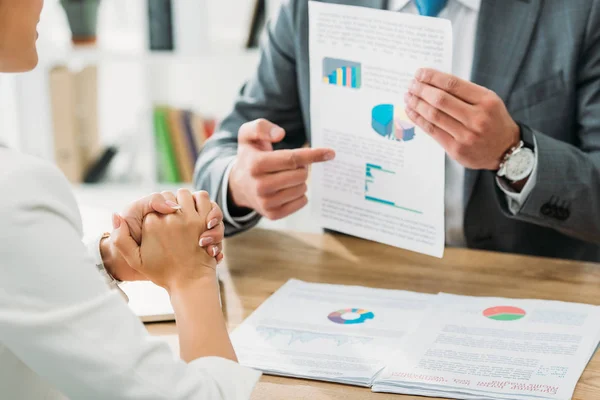 Selective focus of advisor showing and pointing with finger at document — Stock Photo