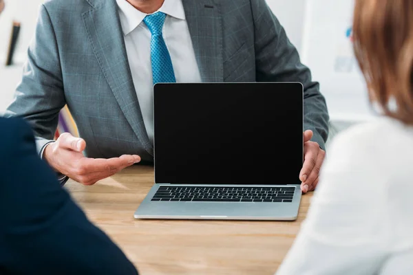 Enfoque selectivo del asesor apuntando con los dedos a la computadora portátil con pantalla en blanco - foto de stock