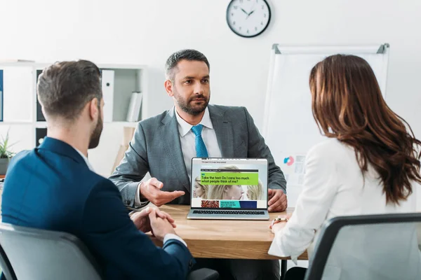 Foyer sélectif du conseiller pointant avec les doigts à l'ordinateur portable avec le site Web de la bbc à l'écran sur le lieu de travail — Photo de stock