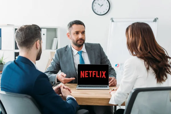 Selective focus of advisor pointing with fingers at laptop with netflix website on screen at workplace — Stock Photo