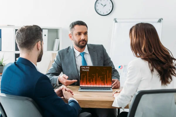 Foco seletivo do conselheiro apontando com os dedos para laptop com site de comércio on-line na tela no local de trabalho — Fotografia de Stock