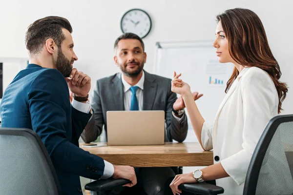 Focus selettivo degli investitori in giacca e cravatta che parlano con il consulente sullo sfondo nello spazio di lavoro — Foto stock