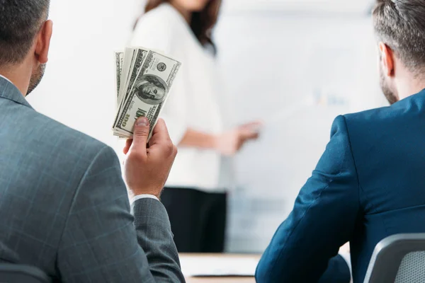 Selective focus of investor holding dollar banknotes with woman on background — Stock Photo