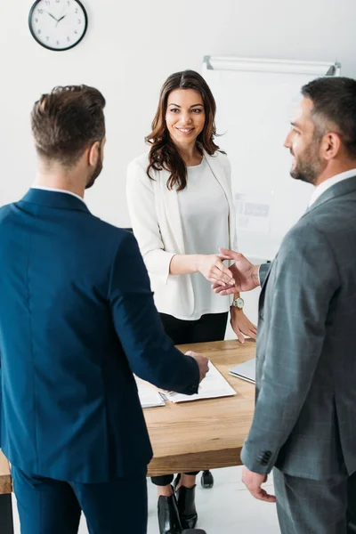 Enfoque selectivo de asesor atractivo y sonriente e inversor estrechando la mano en el lugar de trabajo — Stock Photo